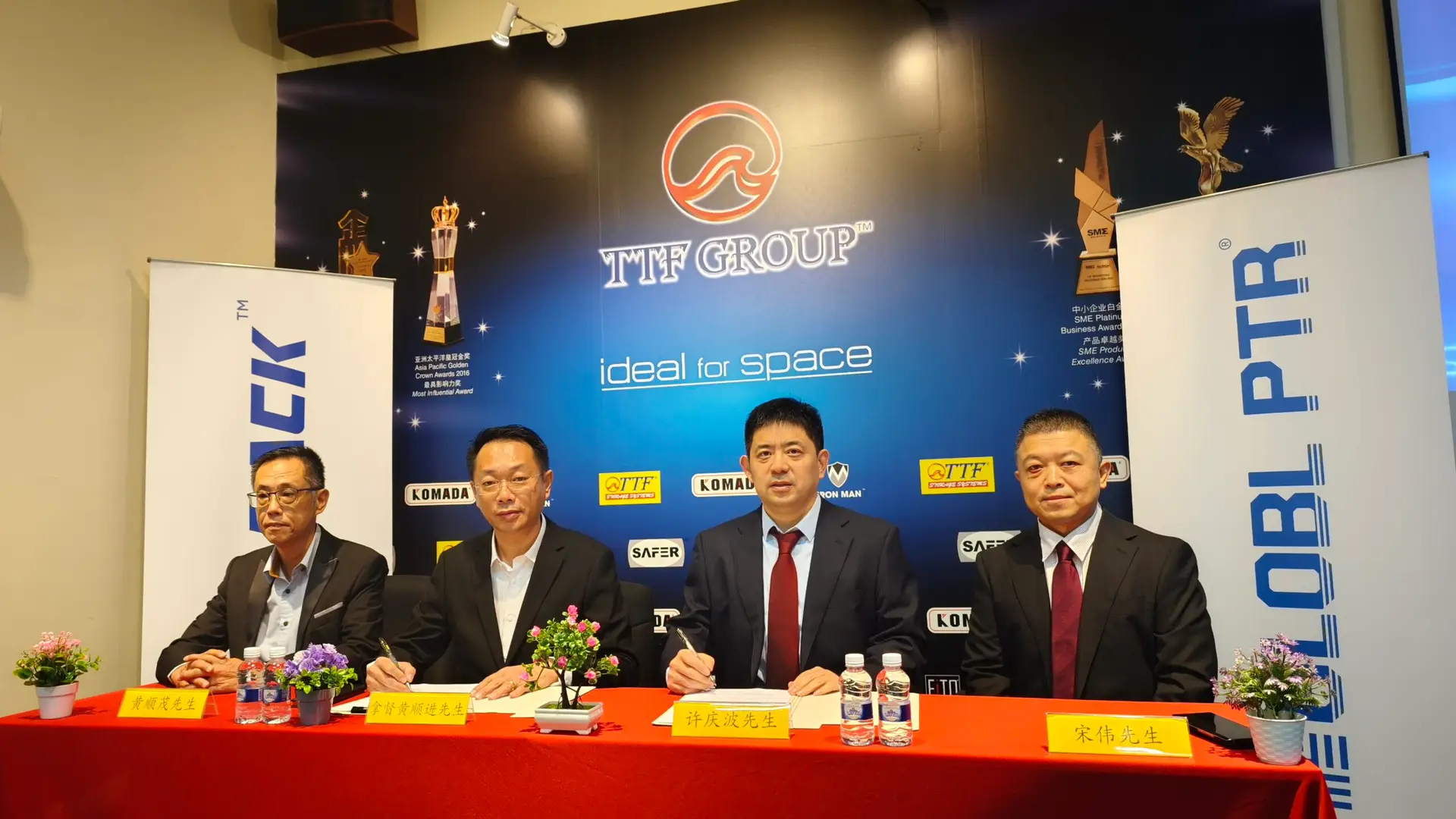 Group photo at TTF Group signing ceremony: Formally dressed Asian businessmen and women smiling and posing with signed agreements. TTF Group logo and awards are displayed, celebrating a successful partnership.