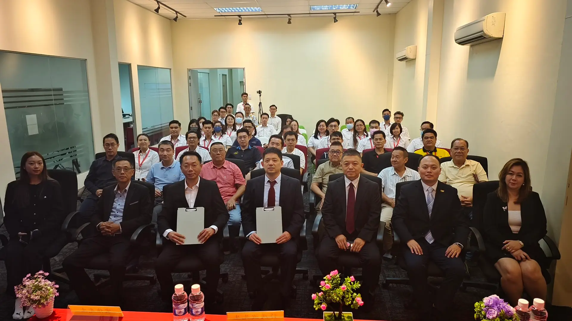 Large group photo at TTF Group office in Rawang, Malaysia: Formally dressed representatives and staff holding certificates after a signing ceremony. The photo captures a moment of celebration and collaboration.